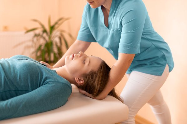 Female physiotherapist or a chiropractor adjusting patients neck. Physiotherapy, rehabilitation concept. Side view cropped shot. Séance d'osteopathie